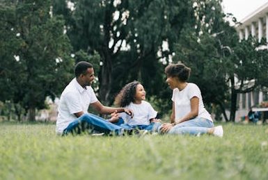 A happy black family enjoying quality time together outdoors in a lush green park.