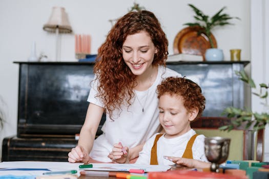 A mother and son enjoy a bonding moment indoors, creating art together with a cozy home atmosphere.